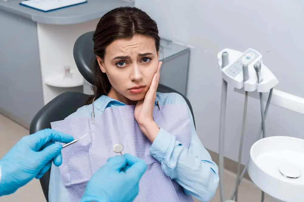 Selective focus of dentist in latex gloves holding dental instruments near upset woman