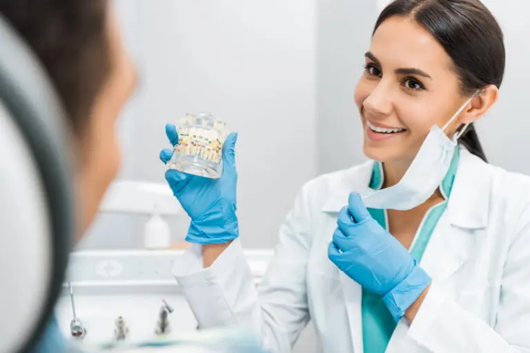 Smiling female stomatologist showing dental jaw model with braces to patient