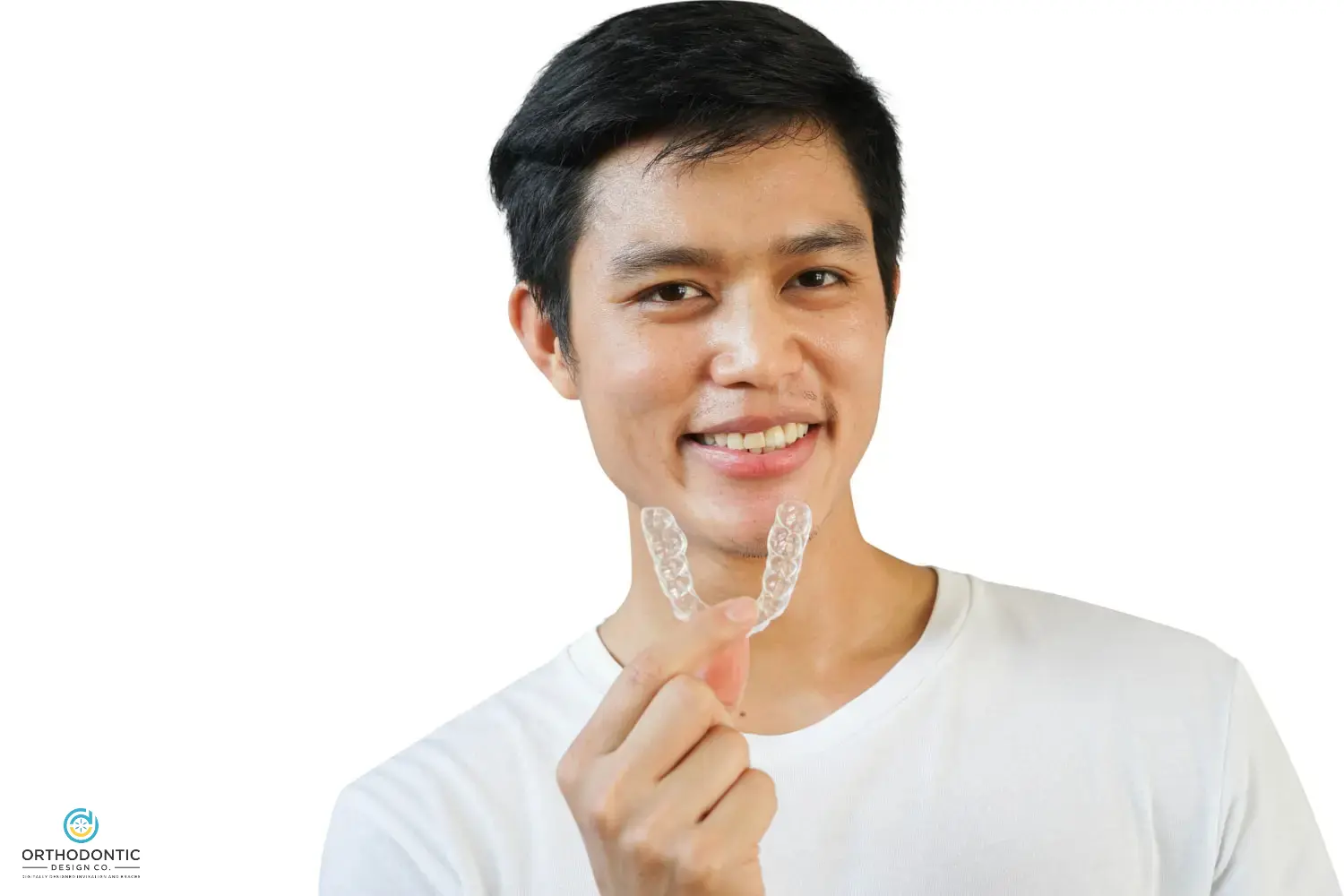 Person smiling and holding a clear orthodontic aligner in front of a white background.