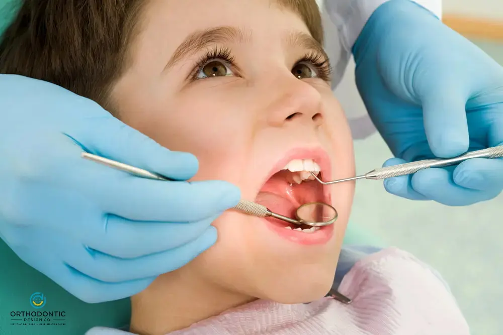 Child at the dentist having teeth examined with dental tools by a dentist wearing blue gloves.