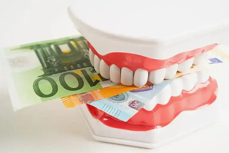 A set of toy chattering teeth holds a money banknote at Orthodontic Design Co in Madison and Huntsville, AL A set of toy chattering teeth holds a money banknote at Orthodontic Design Co in Madison and Huntsville, AL
