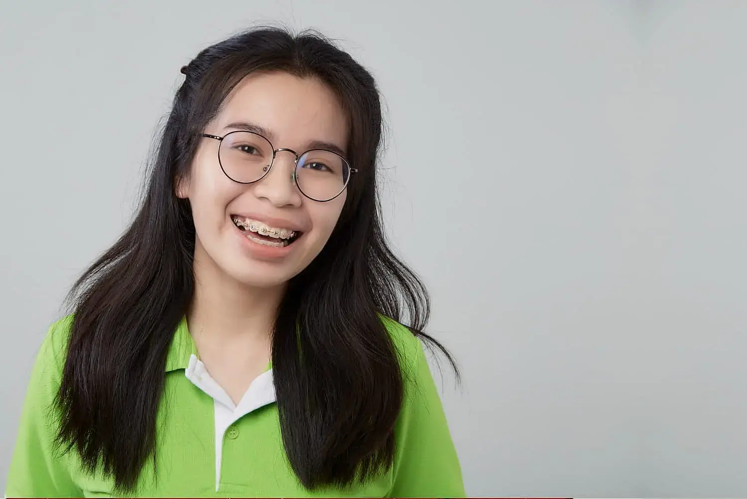 A girl with metal braces smiling and looking upwards at Orthodontic Design Co in Madison and Huntsville, AL