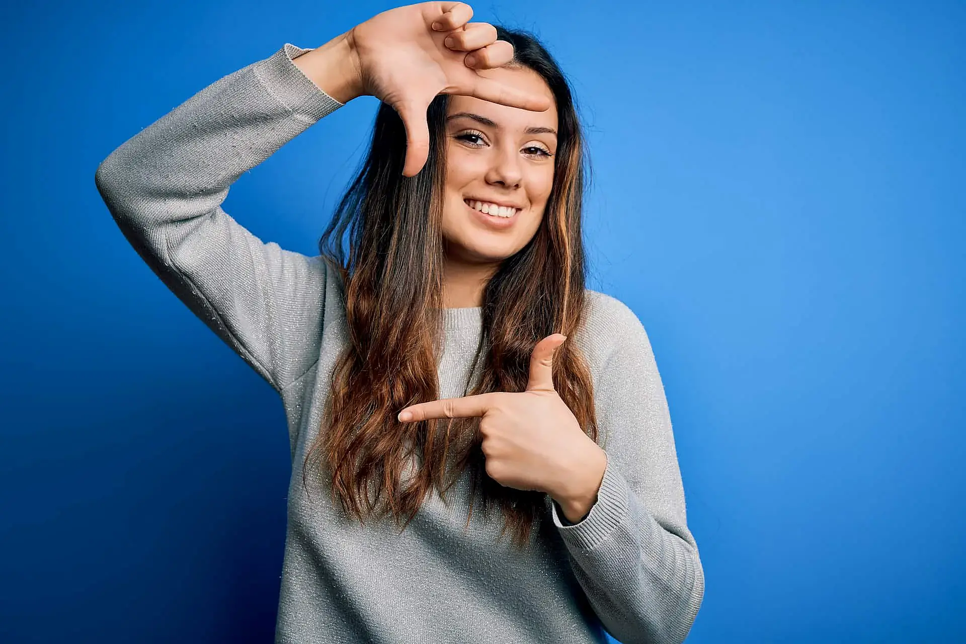 Showcasing the confidence gained from adult orthodontics, a woman smiles against a blue background, framing her face with her hands. Orthodontic Design Co. Orthodontics in Madison and Huntsville, AL can help you achieve this confident smile. Showcasing the confidence gained from adult orthodontics, a woman smiles against a blue background, framing her face with her hands. Orthodontic Design Co. Orthodontics in Madison and Huntsville, AL can help you achieve this confident smile.