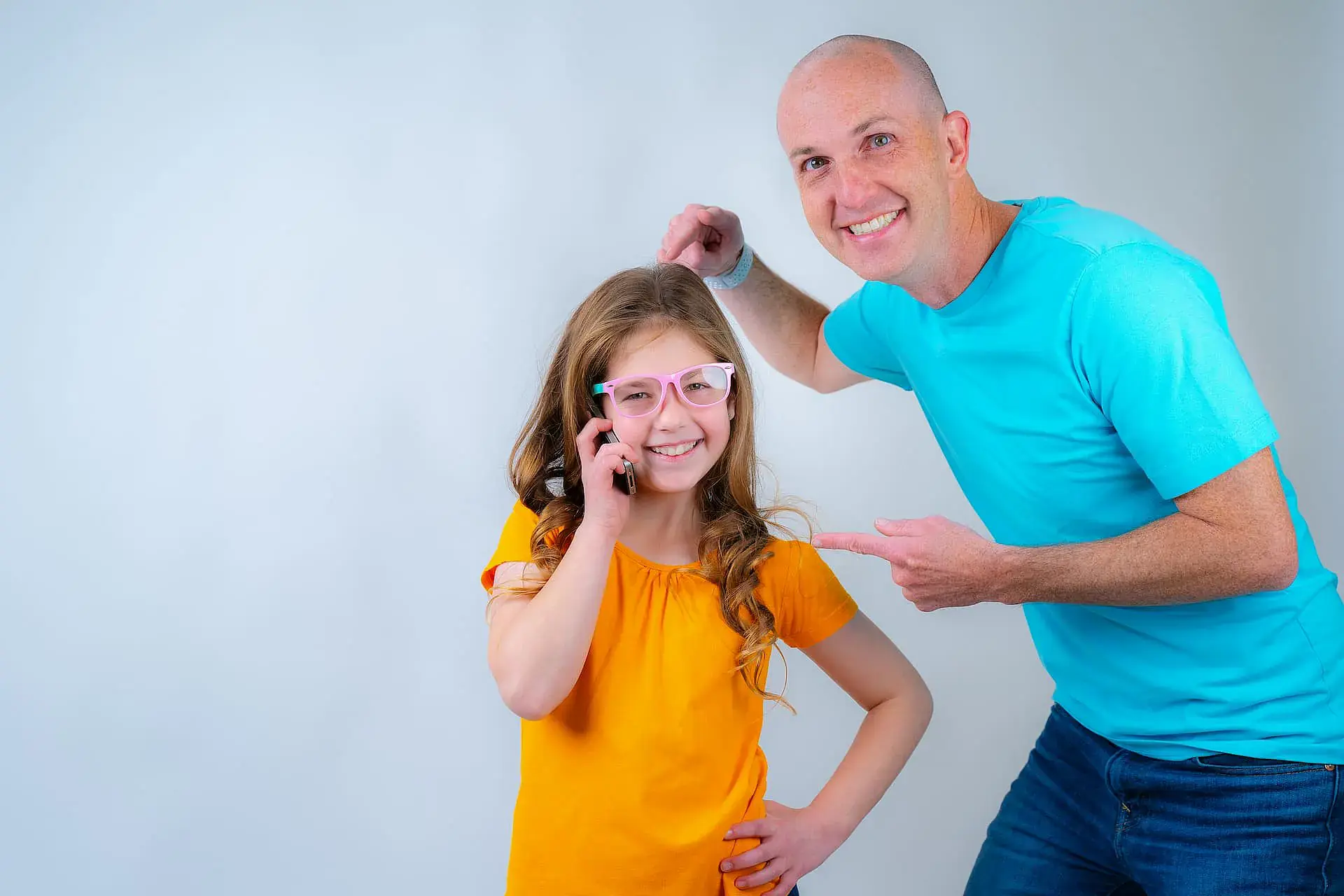 Dr. Adam Reynolds of Orthodontic Design Co. Orthodontics in Madison and Huntsville, AL, smiles while pointing above a happy girl in orange with glasses. Dr. Adam Reynolds of Orthodontic Design Co. Orthodontics in Madison and Huntsville, AL, smiles while pointing above a happy girl in orange with glasses.