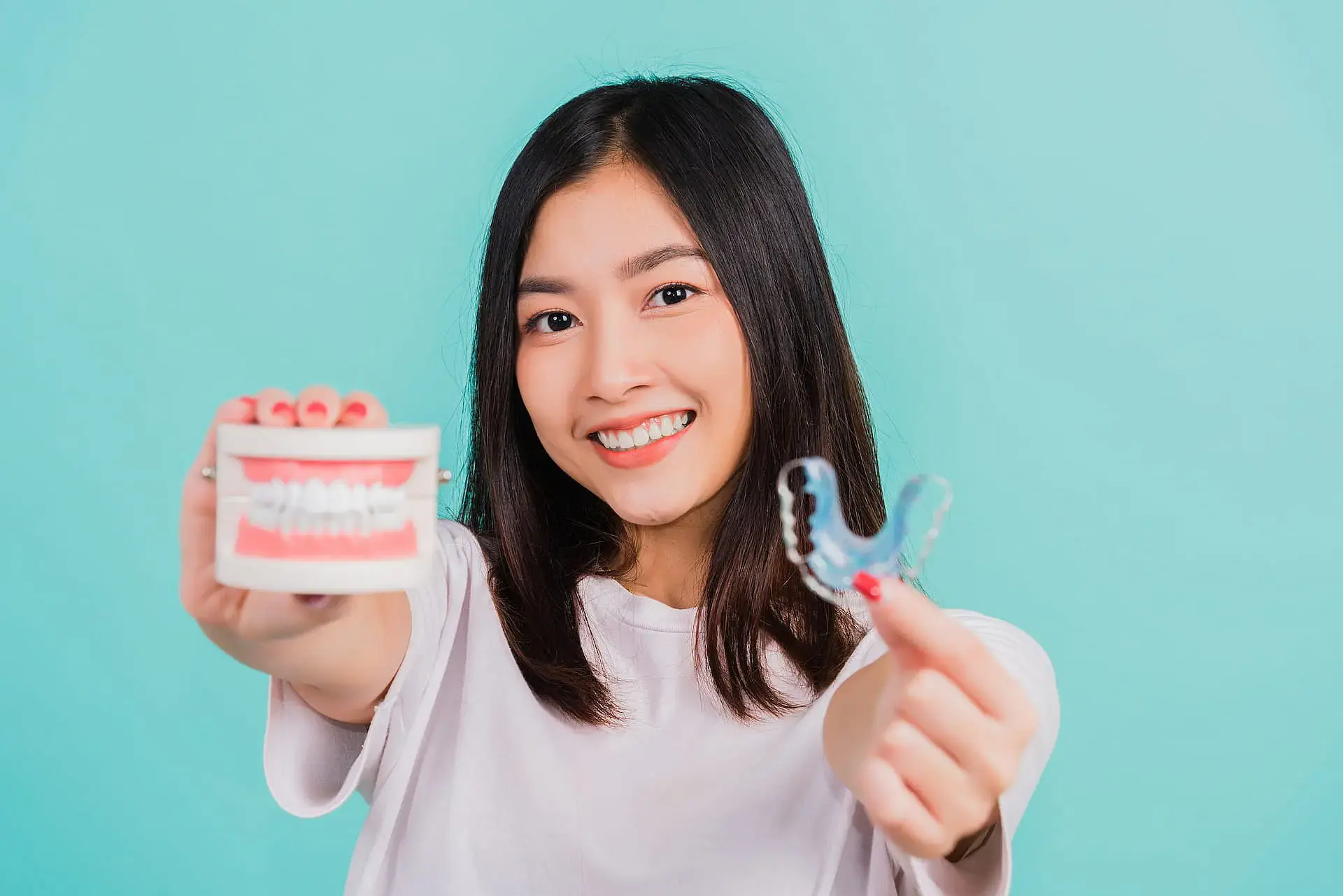 A woman smiles while holding a dental model and clear aligner, showcasing treatment options recommended by a children’s orthodontist at Orthodontic Design Co. Orthodontics in Madison and Huntsville, AL, set against a light blue background. A woman smiles while holding a dental model and clear aligner, showcasing treatment options recommended by a children’s orthodontist at Orthodontic Design Co. Orthodontics in Madison and Huntsville, AL, set against a light blue background.