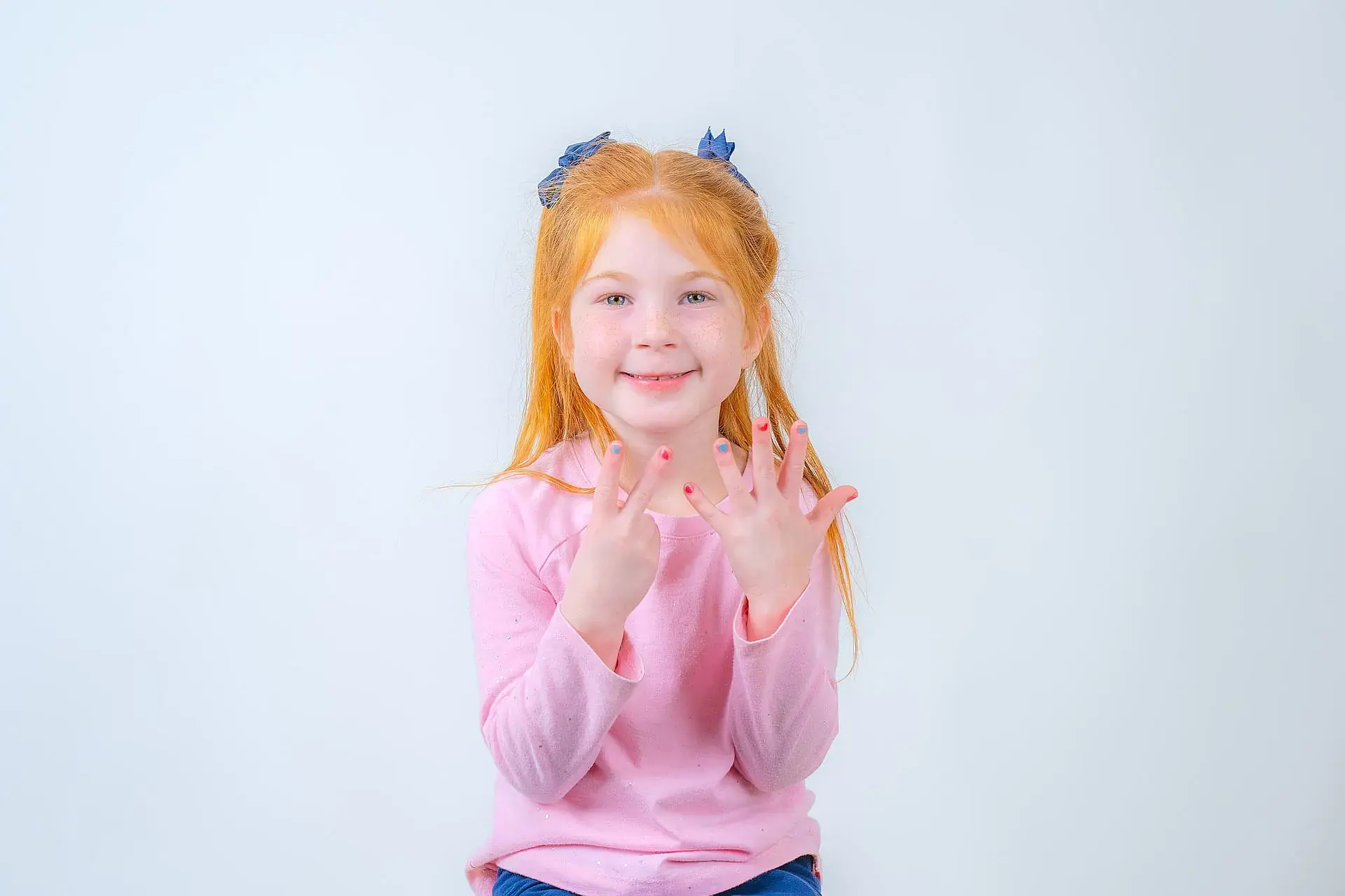 A young red-haired girl in a pink long-sleeve shirt holds up seven fingers and smiles against a plain light background—an ideal image for an Orthodontic Design Co. Orthodontics children’s ad in Madison and Huntsville, AL. A young red-haired girl in a pink long-sleeve shirt holds up seven fingers and smiles against a plain light background—an ideal image for an Orthodontic Design Co. Orthodontics children’s ad in Madison and Huntsville, AL.
