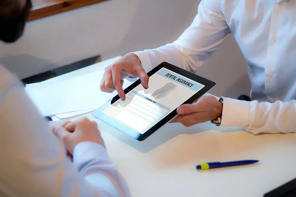At a desk in Madison and Huntsville, AL, two people review a orthodontic insurance plans form from Orthodontic Design Company on a tablet. At a desk in Madison and Huntsville, AL, two people review a orthodontic insurance plans form from Orthodontic Design Company on a tablet.