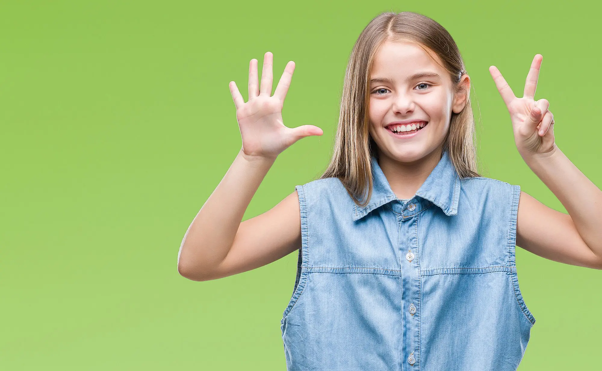 A smiling girl in a sleeveless denim shirt holds up seven fingers, promoting Orthodontic Design Co. Orthodontics in Madison and Huntsville, AL, against a plain green background.