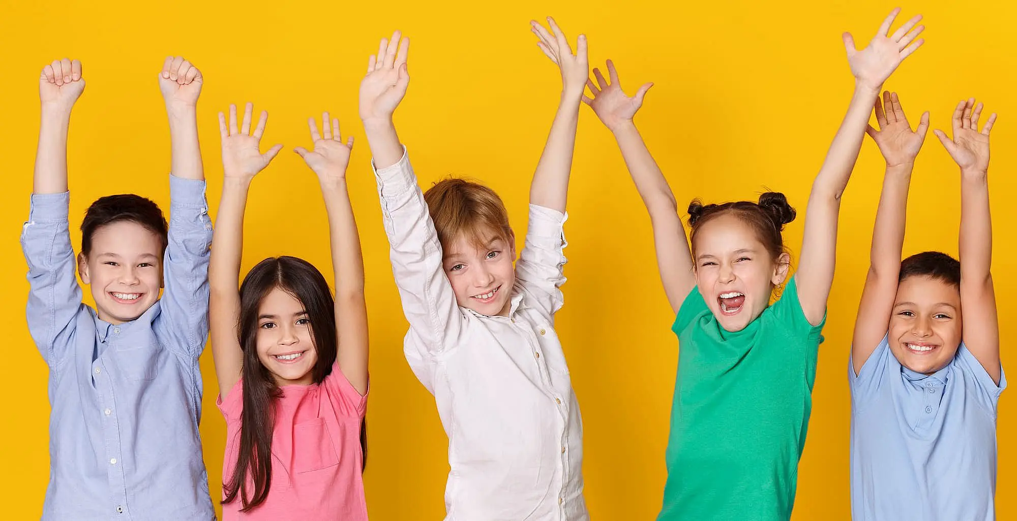 Smiling kids with arms raised stand before a yellow backdrop for Orthodontic Design Co. Orthodontics in Madison and Huntsville, AL.