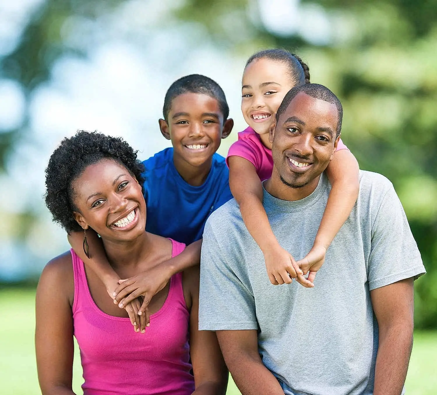 A smiling family of four poses outdoors, looking for Affordable Orthodontic Treatment at Orthodontic Design Co. Orthodontics in Madison and Huntsville, AL.