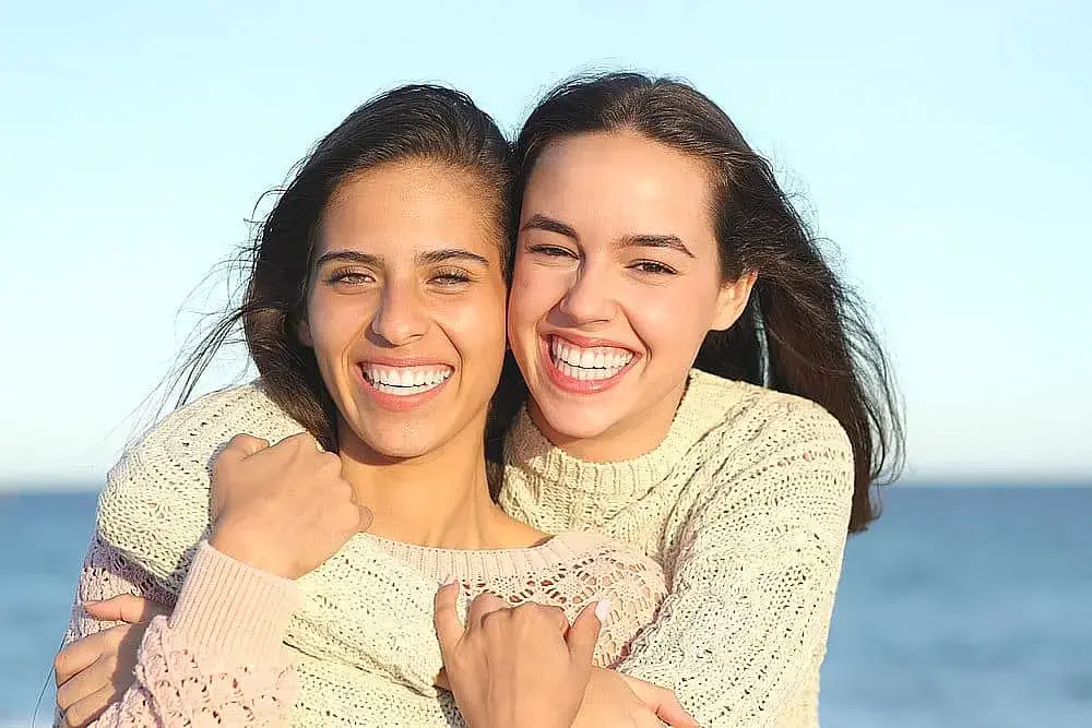 Smiling and hugging, two young women stand by the ocean on a clear day looking for good Invisalign Payment Plan at Orthodontic Design Co. Orthodontics in Madison and Huntsville, AL. Smiling and hugging, two young women stand by the ocean on a clear day looking for good Invisalign Payment Plan at Orthodontic Design Co. Orthodontics in Madison and Huntsville, AL.
