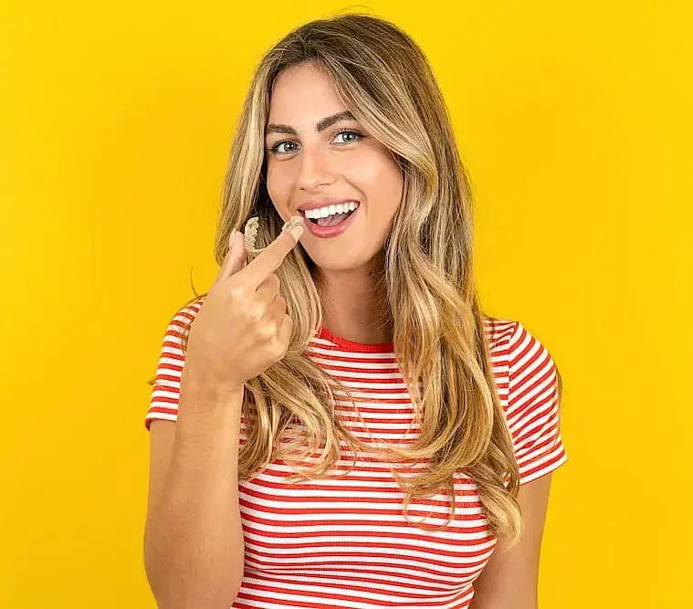 A woman in a red and white striped shirt smiles while using Invisalign aligners to fix her smile at Orthodontic Design Co. Orthodontics in Huntsville, AL. A woman in a red and white striped shirt smiles while using Invisalign aligners to fix her smile at Orthodontic Design Co. Orthodontics in Huntsville, AL.