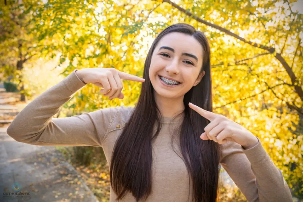 Smiling young woman with braces outdoors, representing Orthodontic Design Co. Orthodontics in Madison and Huntsville, AL - Clear Braces vs Metal Braces in Madison and Huntsville, AL. 