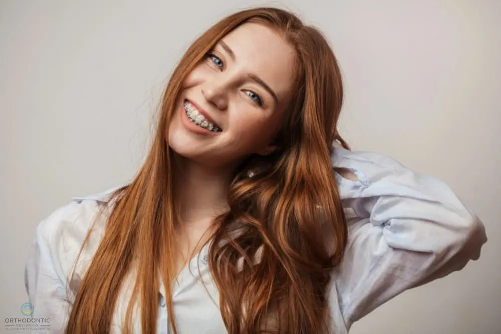 A young woman with red hair and metal braces from Orthodontic Design Co. Orthodontics in Madison and Huntsville, AL smiles - Clear Braces vs Metal Braces in Madison and Huntsville, AL 